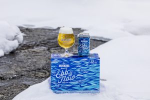 Glass and short can of Ebb and FLow on its 12pack of short cans.